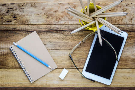 A photo of Tablet and notepad on wood table