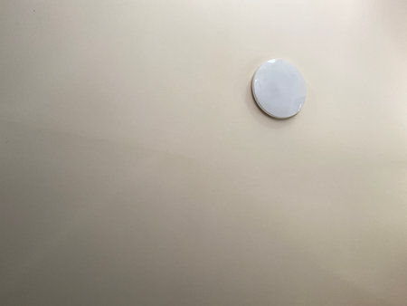 Close up of the corner of a white wall with a round buttonの写真素材