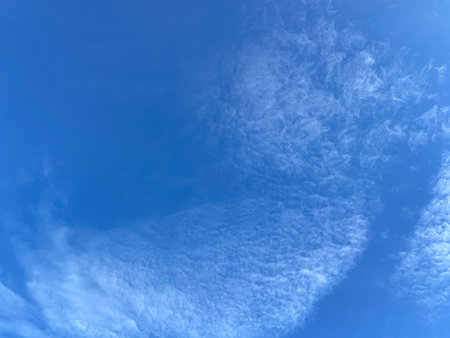 Blue sky background with tiny clouds. White fluffy clouds in the blue sky.の写真素材