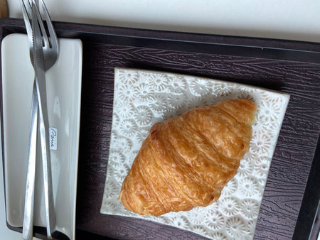 Croissant on a plate with fork and knifeの写真素材