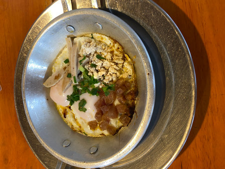 Omelet with pork and egg in hot pot on wooden tableの写真素材