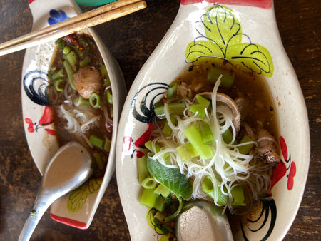 Noodles with pork and vegetables in a bowl on wooden tableの写真素材