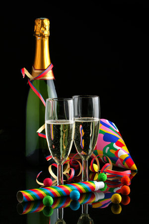 New Year celebration concept with traditional symbols, cup and bottle of champagne, confetti, hats and party accessories, isolated on black backgroundの写真素材