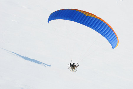 Close-up paramotor flying in winter in a snow-white landscape seen from the skyの写真素材
