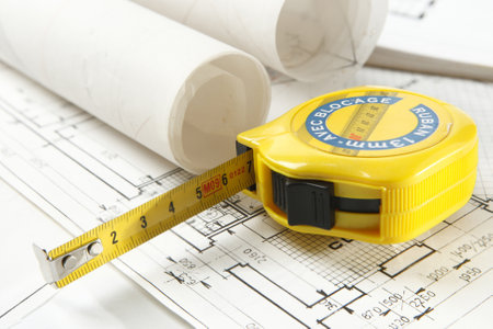 Interior design paper with construction plan in rolls and tape measure close-up