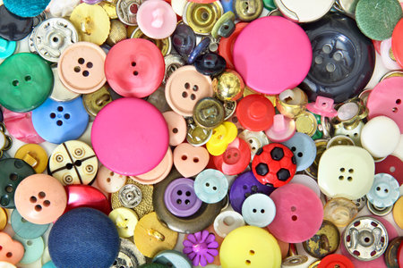 Set of buttons and sewing accessories in very different colors, sizes and shapes. Predominantly pink...