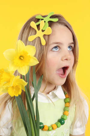 Portrait little girl with daffodils for spring festival on yellow background.の写真素材