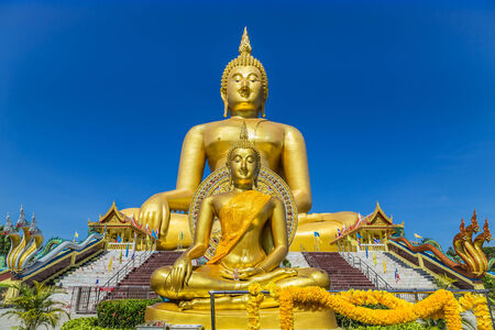 big golden buddha statues sitting at thai temple の写真素材