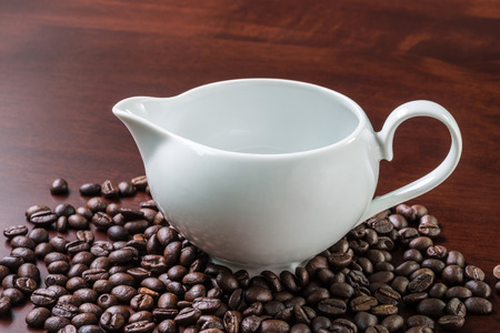 coffee beans spilling out glass bottle on white background の写真素材