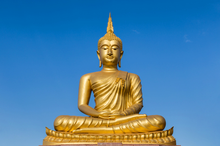 big  golden buddha statue sitting on blue sky white backgroundの写真素材