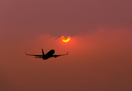 Silhouette airplane flying take off on sunset backgroundの写真素材