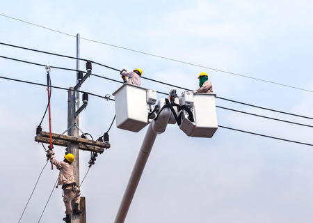 electricians repairing wire of the power line on electric power pole with craneの写真素材
