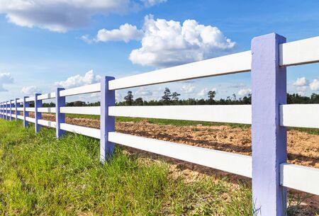 white concrete fence in green farm with blue sky backgroundの写真素材