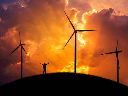 silhouette the man backpacker standing raised up arms achievements successful and celebrate on top of the hill with wind turbines generating electricity in sunset.の写真素材