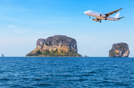 passenger airplane landing above small island in blue sea and tropical beach on blue sky  travel destinations concept.の写真素材