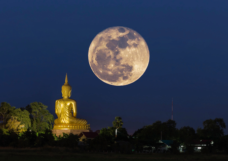 big buddha statue sitting in thai temple at night with super full moonの写真素材