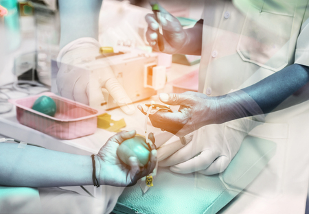Double exposure patient blood donor squeeze red bouncy ball in hand during the transfusion with nurse pricking needle syringe in the arm drawing blood sample for blood testの写真素材