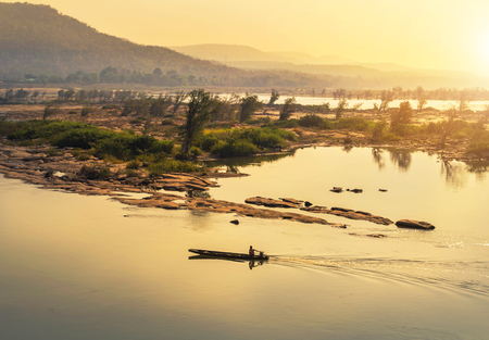 wooden fishing boat sailing in mekong river on sunrise at khongjiam district of thailand border of thailand and laosの写真素材