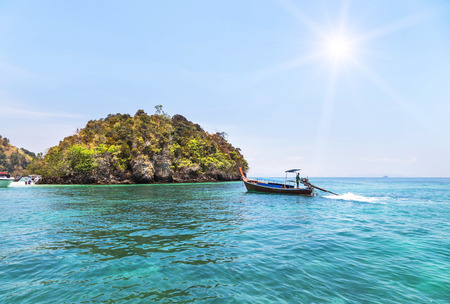 longtail boat sailing on the tropical andaman sea with small limestone island at krabi thailand. longtail boat sailing on the tropical andaman sea with small limestone island at krabi thailand.