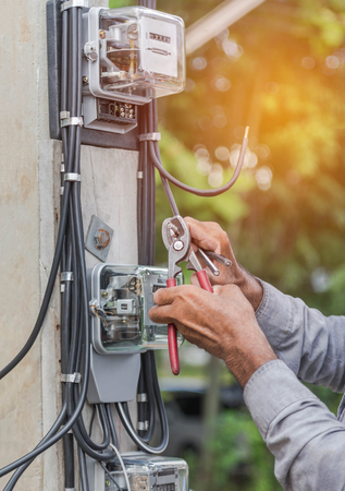 electrician installing electric meter for measuring power into electric line distribution fuseboardの写真素材