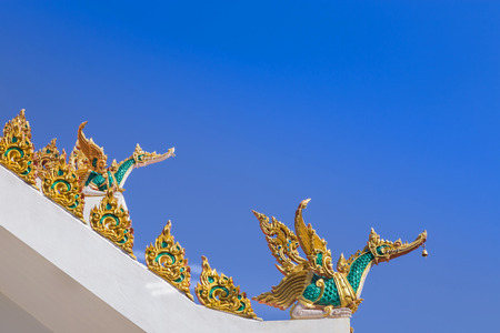 Golden swan traditional thai style statue on roof public temple under blue sky background