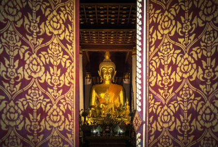 close up public golden buddha statue looks through entrance door in public wat Phra That Chae Haeng public temple at Nan Province, Thailandの写真素材