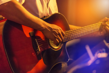 Musician playing acoustic guitar on stage music band in the night at nightclubの写真素材