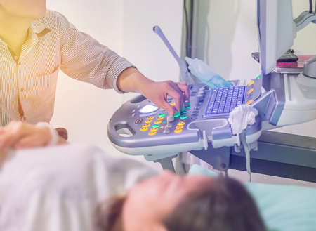 Close up obstetrician diagnostics examining pregnant woman with ultrasound scan equipmentの写真素材