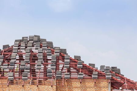 Pile of roof tiles on steel roof frame structures preparing install in residential construction siteの写真素材