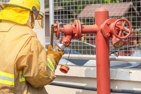 Fireman in yellow fire fighter uniform during connect firehose tube in to fire hydrant during basic...