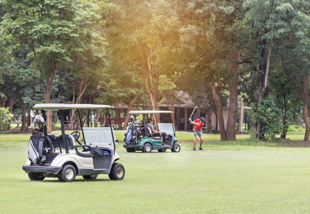 Golf carts parked on fairway during golfer preparing to drive the golf ball in golf courseのeditorial素材