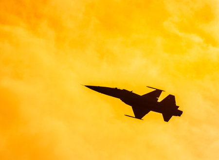 Silhouette fighter jet military aircraft flying with high speed in twilight sunset timeの写真素材