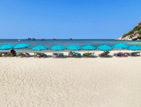 row blue umbrellas with wooden beach chairs on tropical sandy beach in sunny day at Koh Nang Yuan Island Surat Thani, Thailandの写真素材