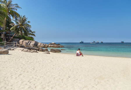 Tourist man sitting relax on the beach  at Koh Nang Yuan paradise island enjoy turquoise water sea with blue sky suratthani , thailandの写真素材