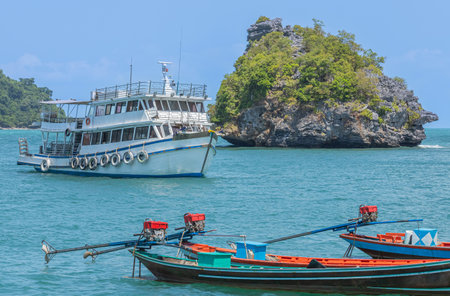 Wooden big boat for tourists diving and longtail boats moored stay in the sea between small limestone islands while tourists divingの写真素材