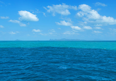 Turquoise blue sea ripple with white clouds on clear blue sky in tropical climateの写真素材
