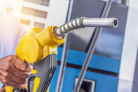 Hand holding fuel nozzle for vehicle on service stationの写真素材