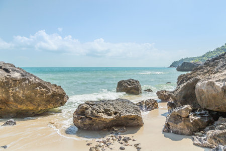 Soft waves in turquoise sea splash crashing rocks in to tropical sandy beachの写真素材