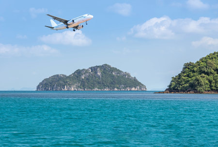 passenger airplane flying above small limestone island in tropical andaman sea , travel destinations conceptの写真素材