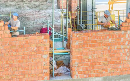 Kiev, Ukraine - July 16, 2018. Workers work at the construction site. Work is under way to lay a wall of red brick.のeditorial素材