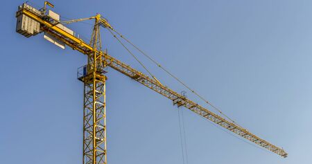 Tower crane at a construction site on a background of blue sky - panorama.の写真素材