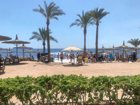 Sharm El Sheikh, Egypt - September 15, 2021: Sunny resort beach with palm trees on the Red Sea coast. Vacationers are having fun.のeditorial素材