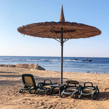 Sharm El Sheikh, Egypt. Sunny resort beach on the shores of the Red Sea. National style beach umbrella made of natural materials.の写真素材