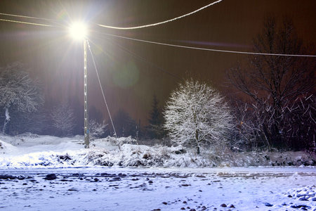 Winter landscape with snow covered trees and street lights in the city, Poland.