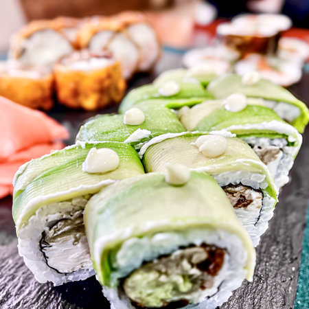 Sushi rolls with eel, avocado, cream cheese and cucumber on a black background.の写真素材