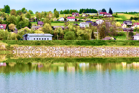 village on the shore of a lake with reflections in the waterの写真素材