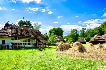 Old wooden house with hay bales on the meadow in the villageの写真素材