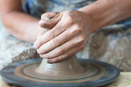Potter hands making in clay on pottery wheel. Potter makes on the pottery wheel clay pot.