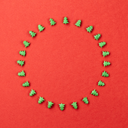 Christmas round frame of a fir-trees on a red backgroundの写真素材