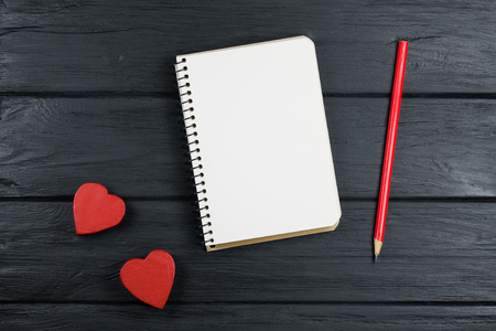The romantic background with notepad, pencil and two red hearts.の写真素材